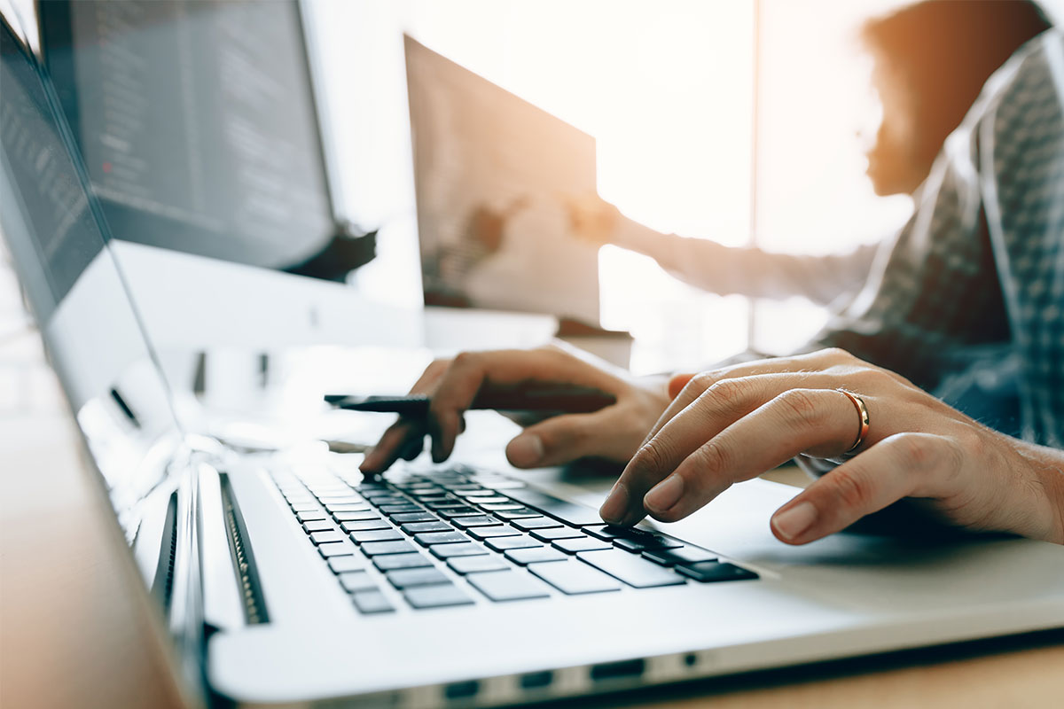 Woman typing on work computer and her desk.