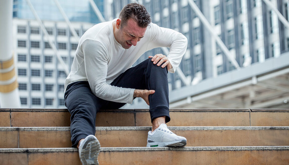 A Man Sitting on Stairs Holding His Calf in Pain Ruptured Achilles vs Torn Achilles