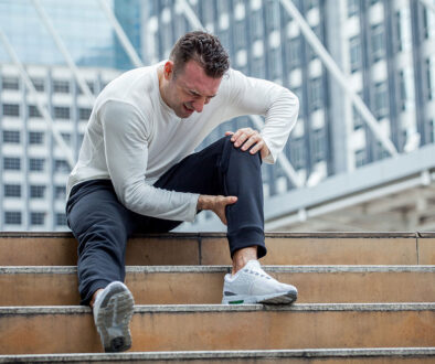 A Man Sitting on Stairs Holding His Calf in Pain Ruptured Achilles vs Torn Achilles