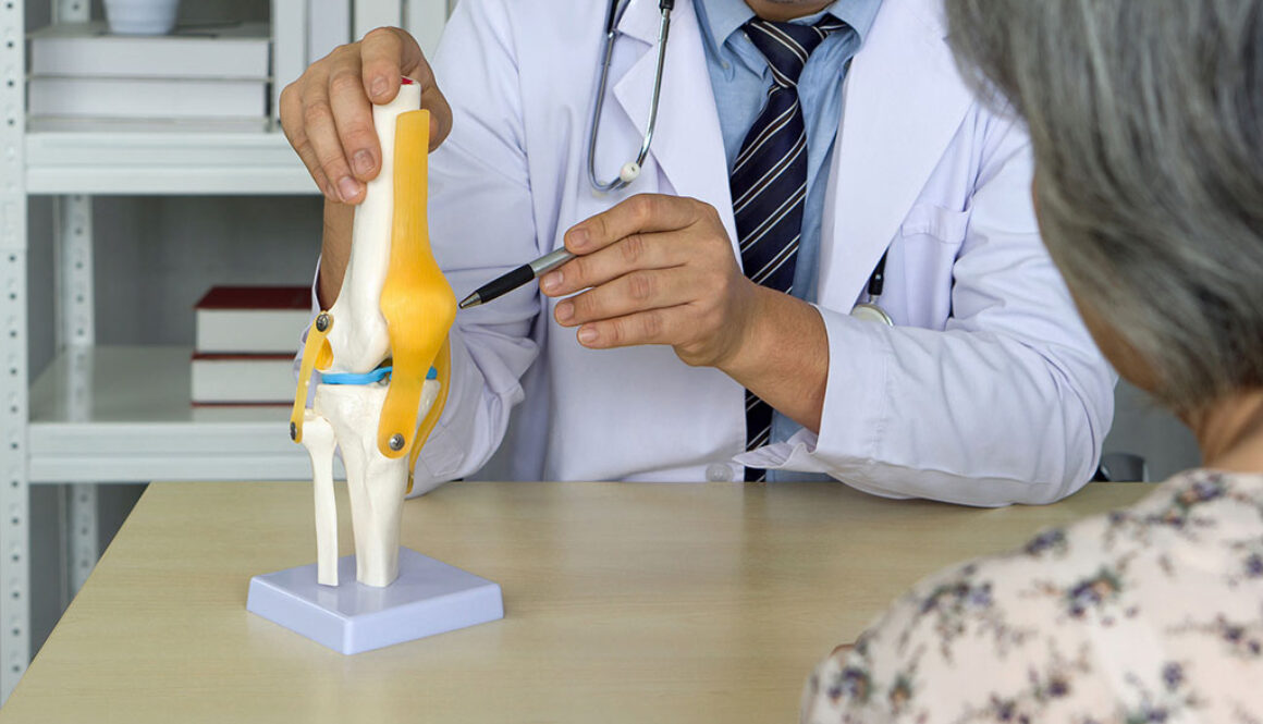 Closeup of a Board-Certified Orthopedic Doctor Pointing to a Model of a Knee With a Patient