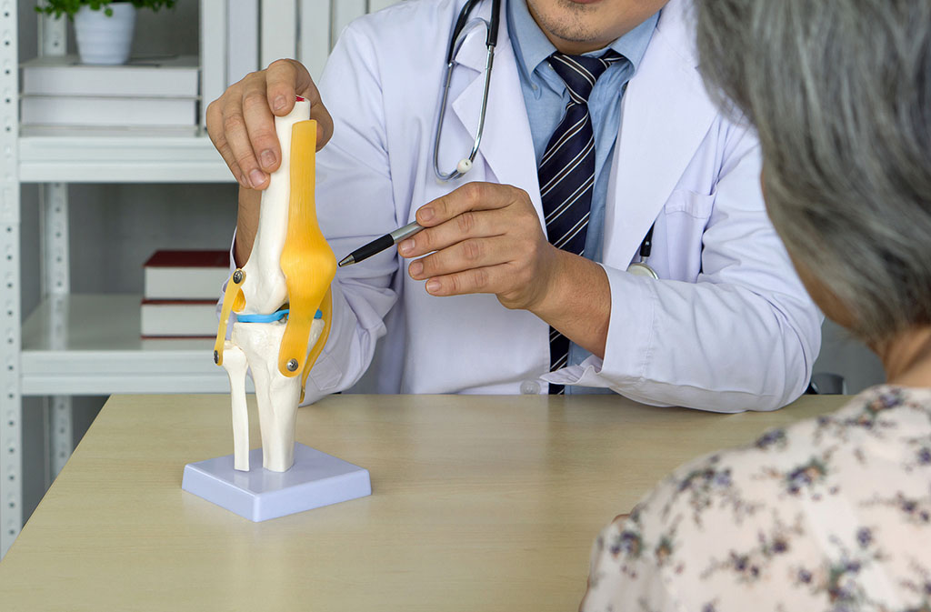 Closeup of a Board-Certified Orthopedic Doctor Pointing to a Model of a Knee With a Patient